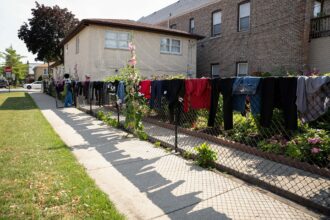 Delia and Ramon Vasquez's stiff jeans and soaking wet T-shirts hang over the wire fence surrounding their home in Cicero, Ill., July 3, 2023.