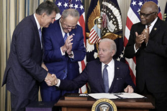 President Joe Biden shakes hands with Sen. Joe Manchin (D-WV) (L) after signing the Inflation Reduction Act on Aug. 16, 2022, with Senate Majority Leader Charles Schumer (D-NY) and House Majority Whip James Clyburn (D-SC) in the State Dining Room of the White House. Credit: Drew Angerer/Getty Images.