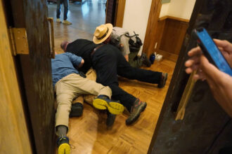Three members of security and law enforcement tackle Teddy Ogborn last week at the Jackson Lake Lodge, where the Jackson Hole Economic Symposium was being held in Jackson Hole Wyoming. Credit: Climate Defiance