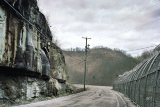 The prison fence at the Southeast State Correctional Complex in Floyd County, Kentucky, meets a road and open coal seam. Credit: Jill Frank