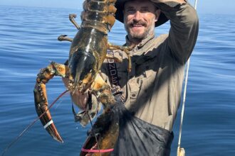 Some large lobsters are still around. Josiah Mayo stands on board Mike Packard’s F/V J&J with a nine-pound lobster in a photo taken two weeks ago. Credit: Mike Packard/Provincetown Independent.