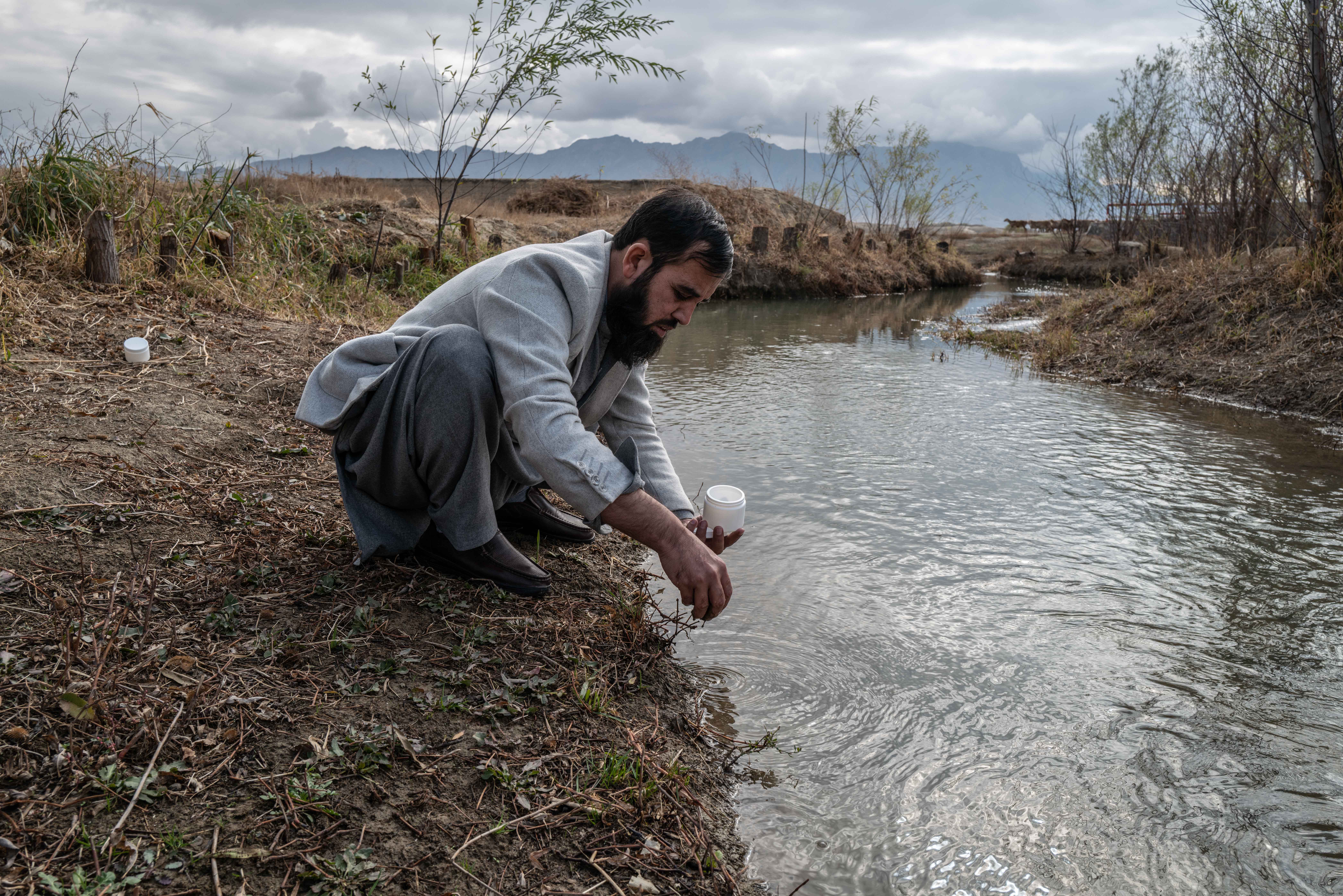 An Afghan scientist gathers water and soil samples at a water outflow from Bagram Airfield, formerly America's largest military base in Afghanistan. Credit: Kern Hendricks