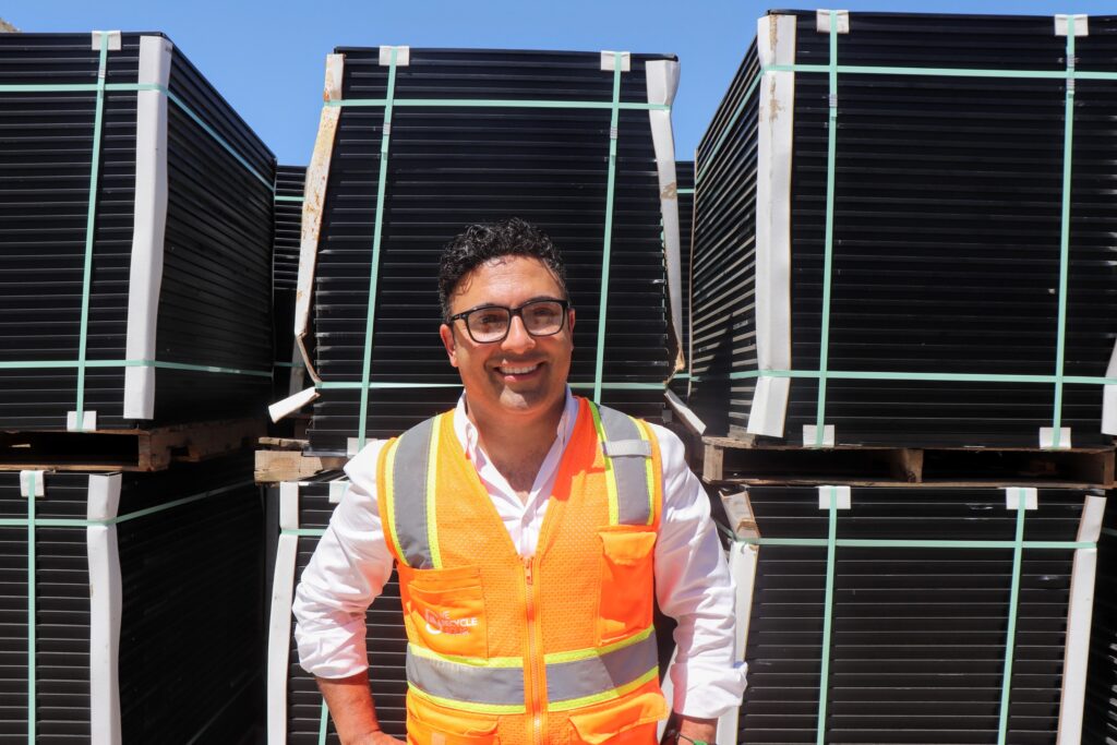 Adam Saghei, CEO of We Recycle Solar, stands in front of pallets of resell-ready solar panels on August, 8, 2023 at the company's facility in Yuma, Ariz. Credit: Emma Peterson.